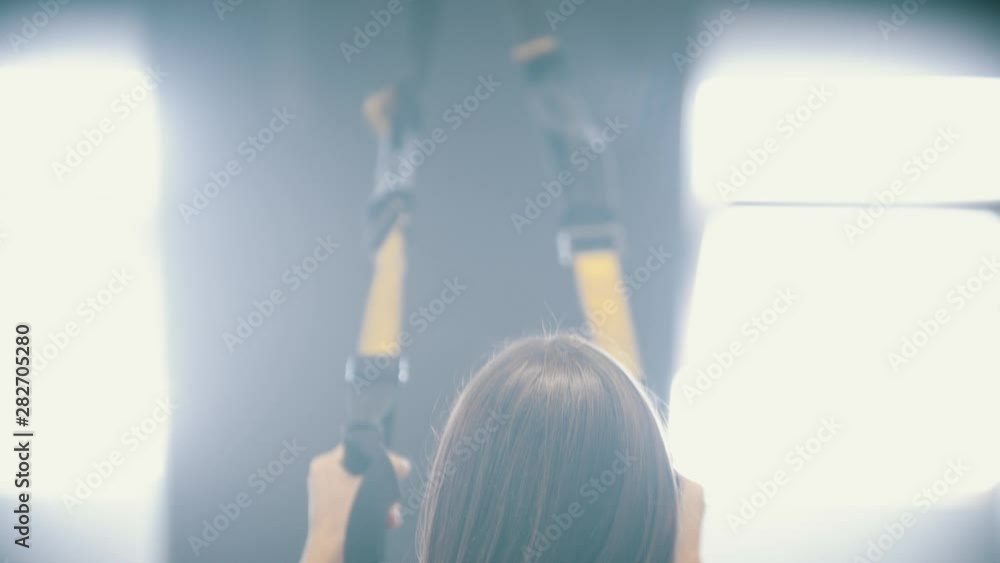 A woman training in the gym - holding the handles and doing down on the knee - training the butt A woman training in the gym - holding the handles and doing down on the knee - training the butt