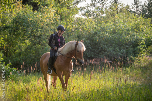 Woman horseback riding in forest and meadow