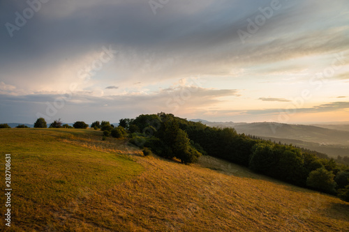 Landscape view on meadow with blue sky with many clouds and forest close to city Valasske Mezirici captured during summer late time.