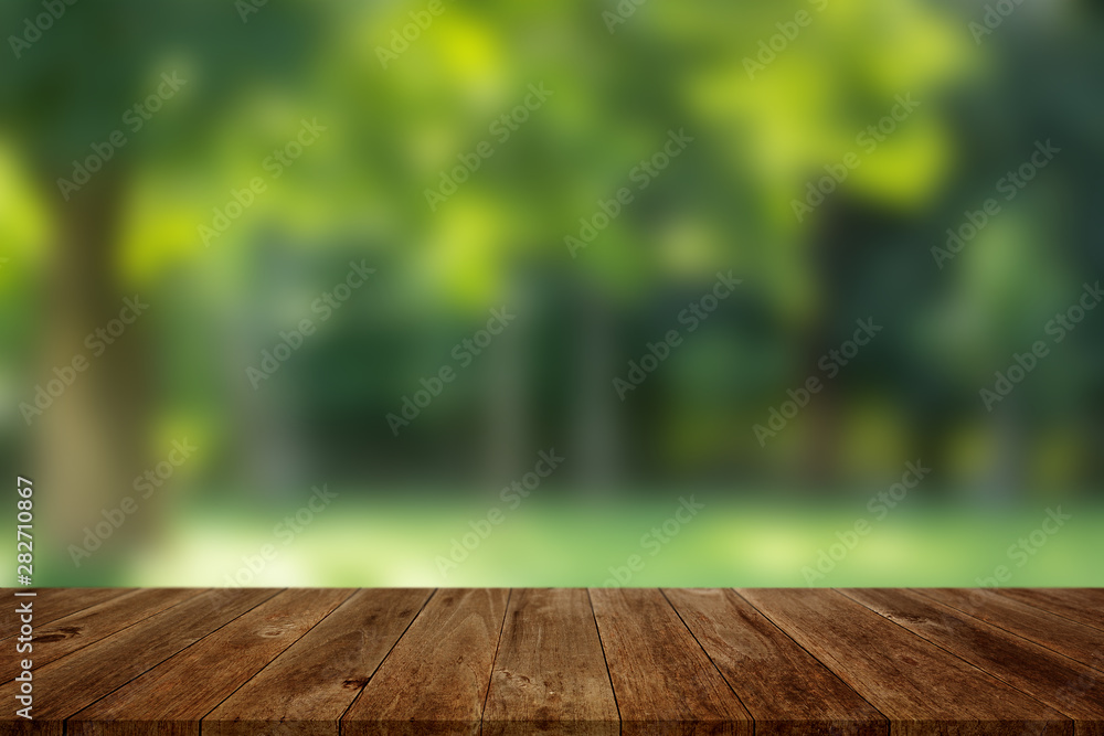 Wood floor with blurred trees of nature park background and summer season, product display montage Wood floor with blurred trees of nature park background and summer season, product display montage