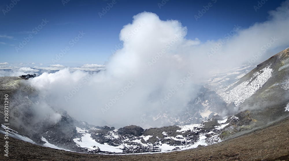 The beautiful crater of volcano etna producing smoke.