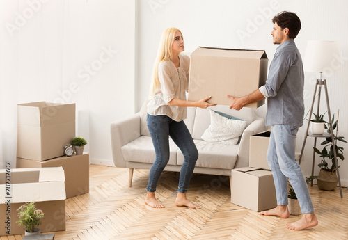 Worried Man And Woman Carrying Moving Box In New Apartment