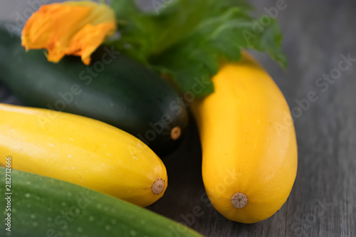 Yellow and green zucchini on a gray wooden background.