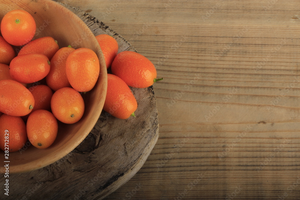 kumquat in wooden plate on wooden background. top view kumquat in wooden plate on wooden background. top view