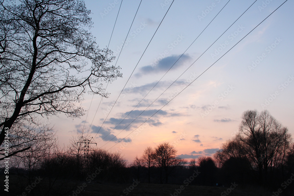 Obraz premium High voltage transmission towers silhouette on sunset and twilight sky.