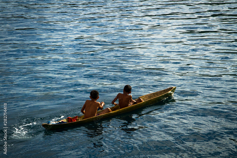 Fototapeta premium Local fisherman young boys play on the small traditional paddle boat