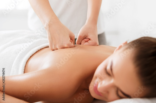 Professional therapist doing back massage to woman