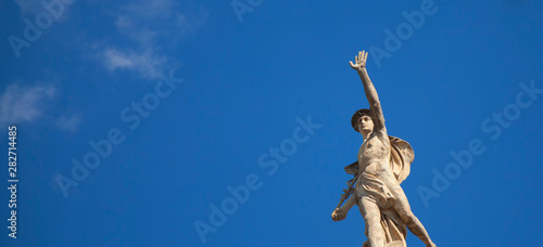 Ancient statue of the antique god of commerce, merchants and travelers Hermes (Mercury) against blue sky. He is alsow olympic gods messenger with wings on a helmet. photo