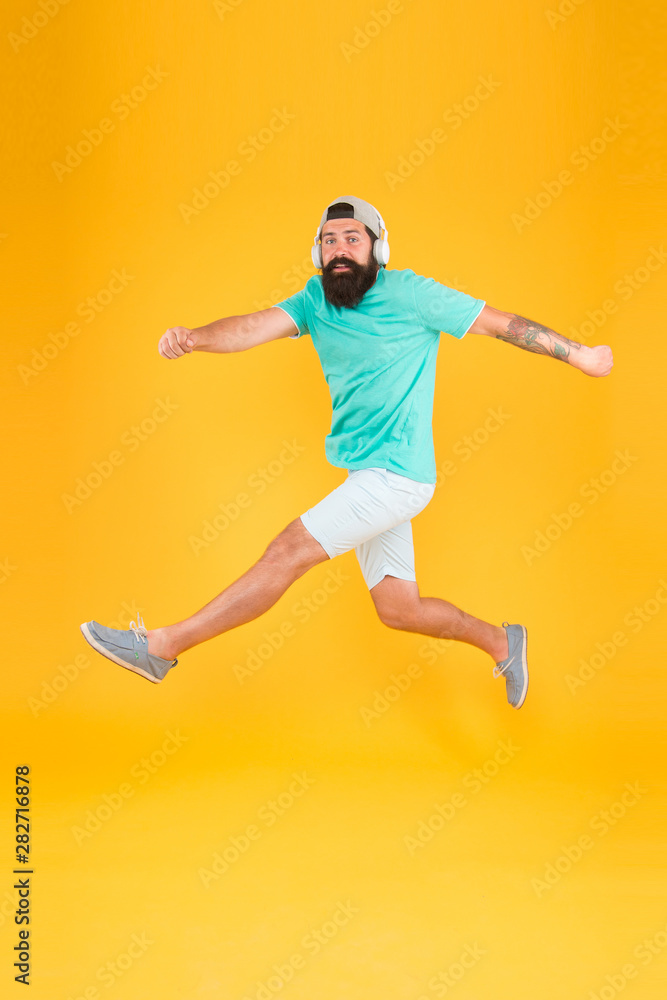 Energetic and upbeat music for leisure. Energetic hipster jumping high on yellow background. Bearded man in mid air. Brutal guy enjoying energetic music. Active and energetic