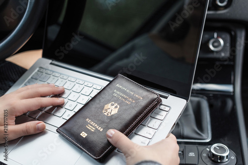Woman in the car with laptop and germany passport. Travel concept.