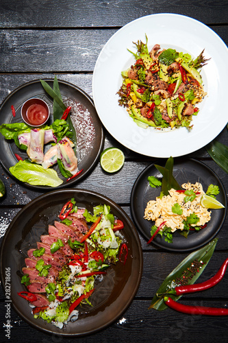 Asian dishes on a black table. Salads and snacks