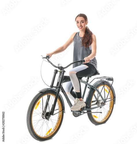 Sporty young woman riding bicycle against white background