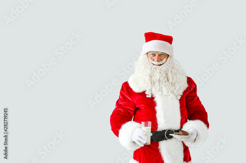 Portrait of Santa Claus with milk and cookies on light background