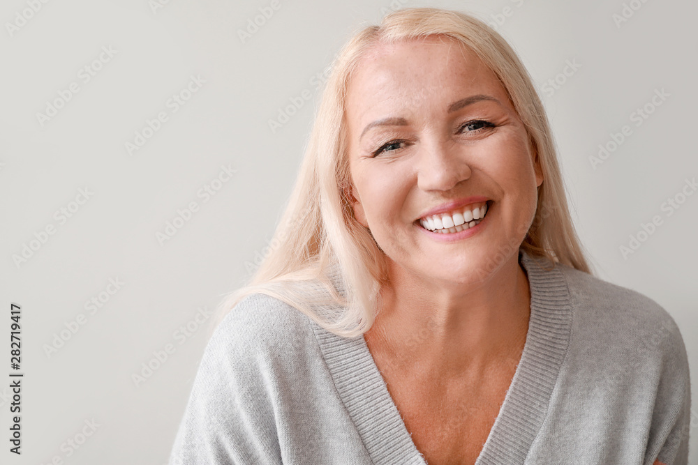 Happy mature woman on grey background Happy mature woman on grey background