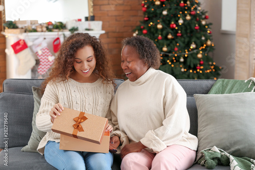 Portrait of African-American woman and her daughter with Christmas gift at home