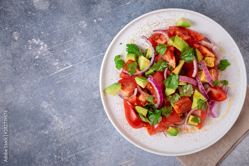 Vegetarian salad with avocado, tomato and red onion. Top view, copy space