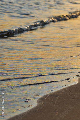  Sandy beach with blurred sea water on a sunset as a natural background. Copy space. 