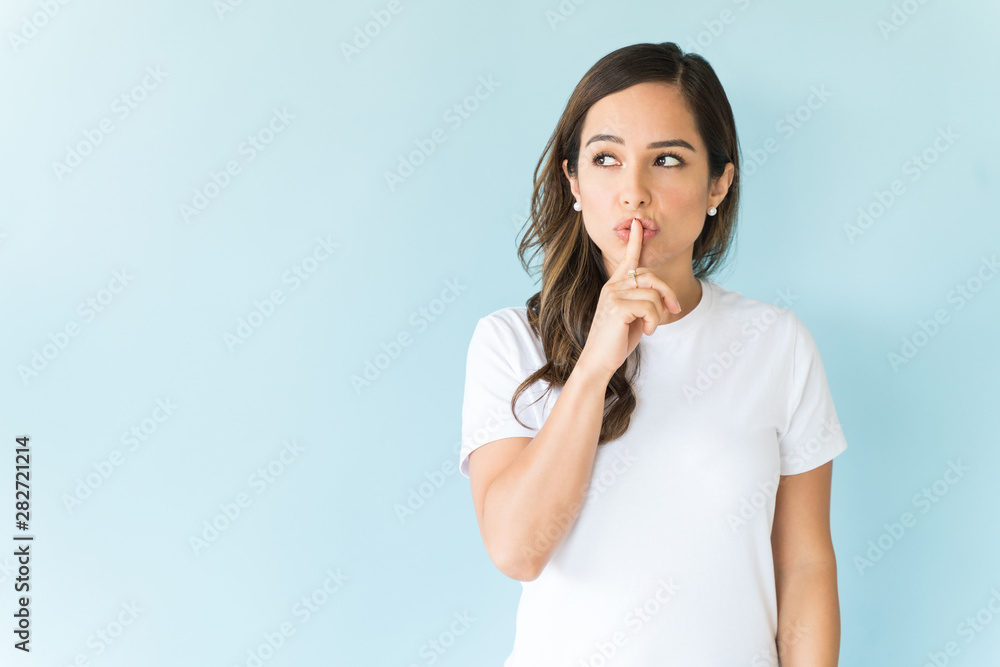 Female Model Is Standing With Finger On Lips In Studio Female Model Is Standing With Finger On Lips In Studio