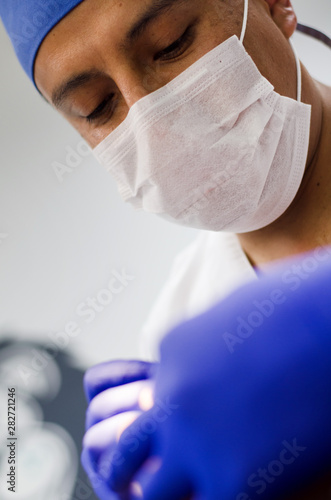 Dentist leaned over patient in dentist s chair at clinic. Doctor with mask and tools