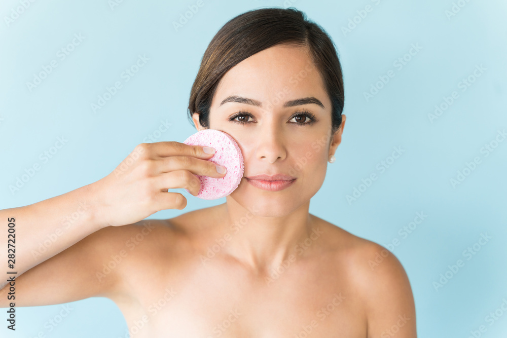 Beautiful Woman Is Scrubbing Face Against Colored Background - obrazy, fototapety, plakaty 