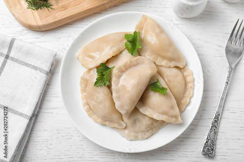Tasty cooked dumplings served on white wooden table, flat lay