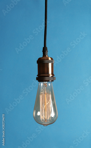 Hanging modern lamp bulb against blue background