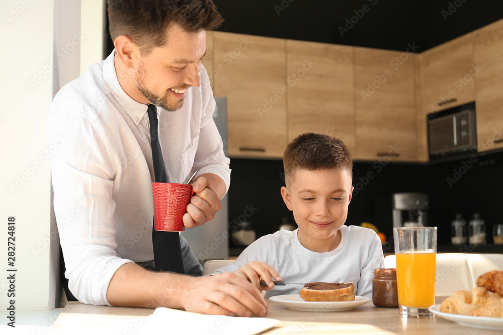 Dad and son having breakfast together in kitchen Dad and son having breakfast together in kitchen