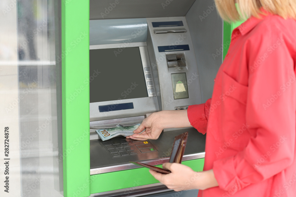 Woman taking money from cash machine outdoors, closeup Woman taking money from cash machine outdoors, closeup