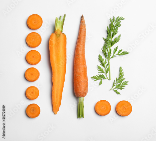 Fototapeta Cut carrots and leaves isolated on white, top view