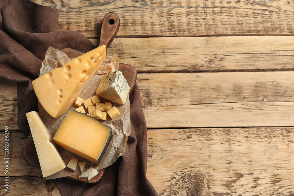 Different delicious cheeses served on wooden table, top view. Space for text