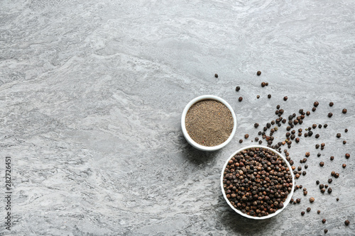 Ground black pepper and corns on grey table, top view. Space for text
