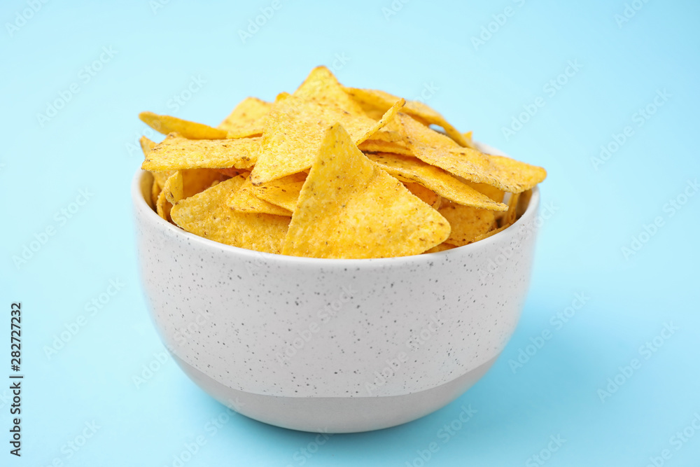 Bowl with tasty Mexican nachos chips on light blue background Bowl with tasty Mexican nachos chips on light blue background
