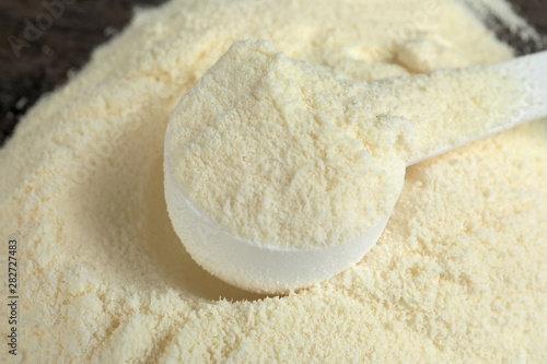 Pile of protein powder and scoop on table, closeup