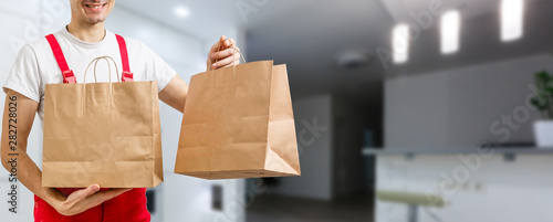 delivery, mail and people concept - happy man delivering food in disposable paper bag to customer home photo