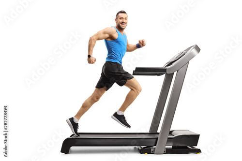 Young man in sportswear running on a treadmill and looking at the camera