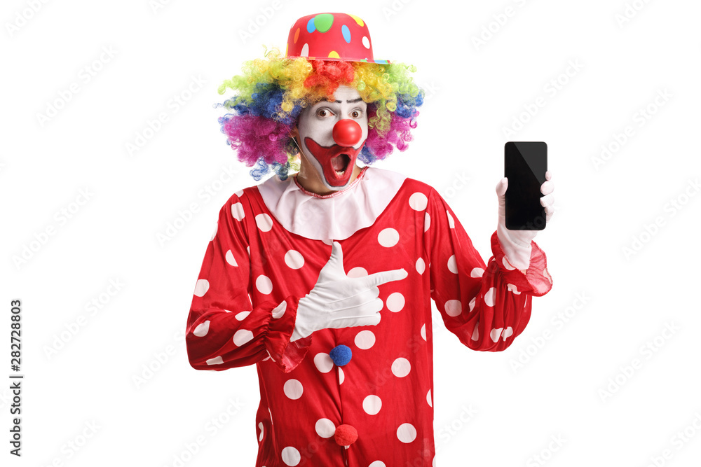 Cheerful clown holding a mobile phone and pointing at it