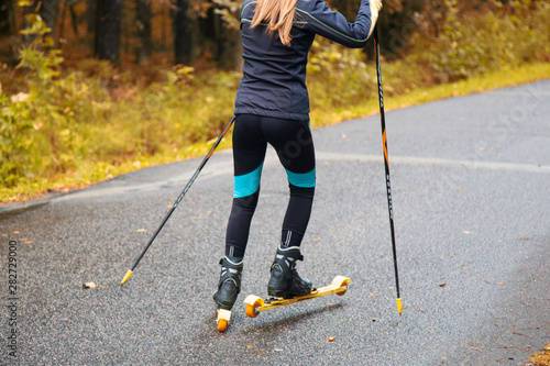 Woman cross-country skiing with roller ski in park
