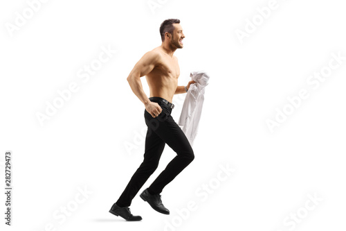 Young handsome man running shirtless and holding a shirt in his hand