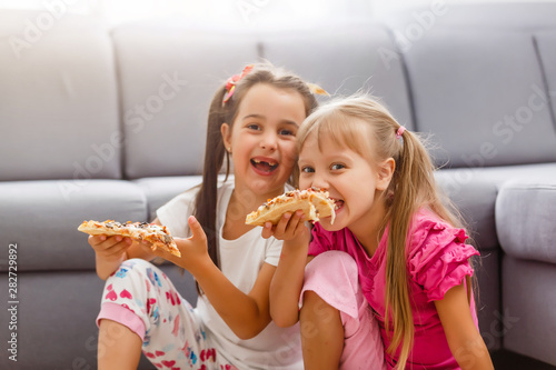 Portrait of cute little girl sitting and eating pizza