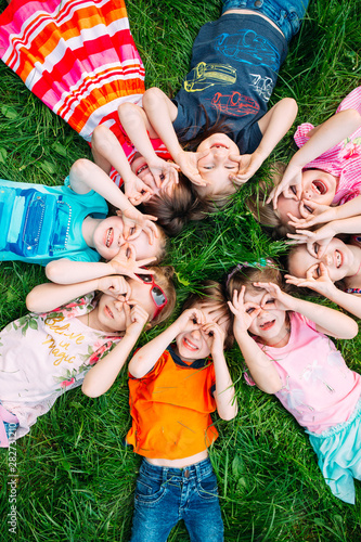 Obraz na plátně A group of children lying on the green grass in the Park