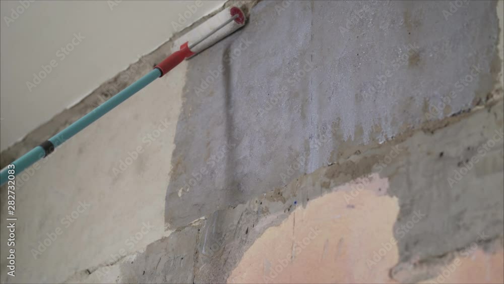Primed walls with a roller. Background of wet concrete wall. The concept of apartment renovation, construction and finishing works, the Primed walls with a roller. Background of wet concrete wall. The concept of apartment renovation, construction and finishing works, the