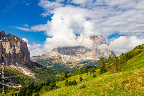 colorful top view to Sassolungo mountain in the clouds on a Sunny summer day from Passo Sella di val Gardena Dolomites, South Tyrol, alto adige, Italy. Langkofel in the Dolomiti Alps above Pass Pordoi