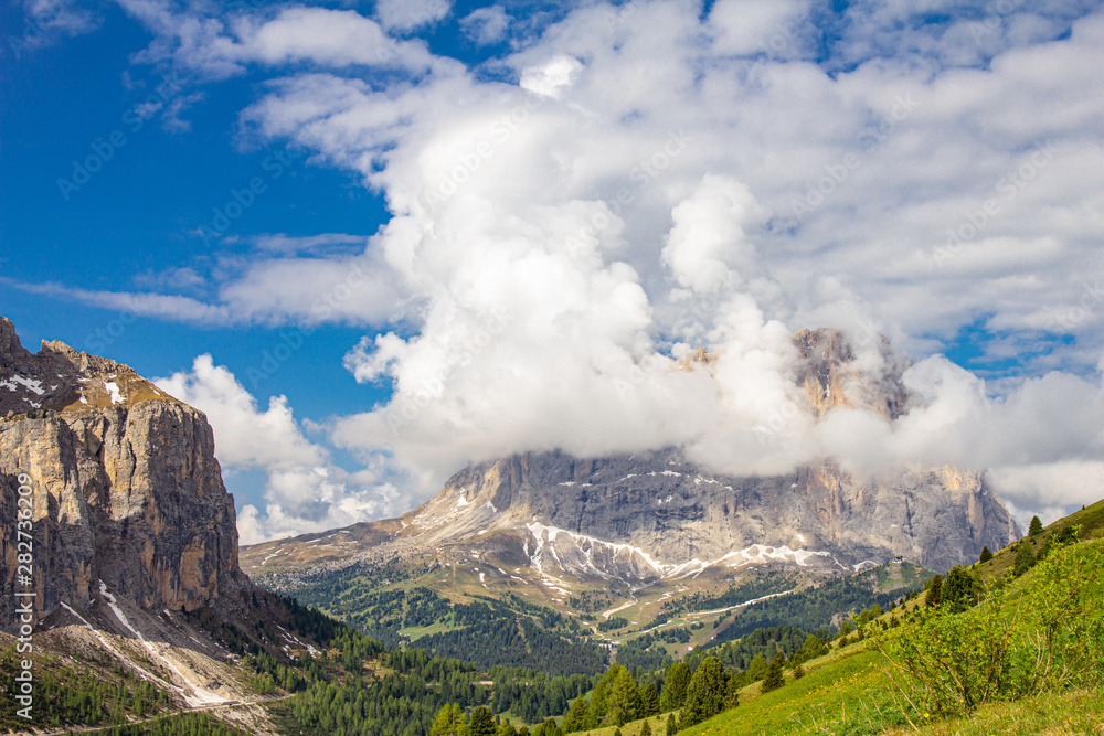 colorful top view to Sassolungo mountain in the clouds on a Sunny summer day from Passo Sella di val Gardena Dolomites, South Tyrol, alto adige, Italy. Langkofel in the Dolomiti Alps above Pass Pordoi colorful top view to Sassolungo mountain in the clouds on a Sunny summer day from Passo Sella di val Gardena Dolomites, South Tyrol, alto adige, Italy. Langkofel in the Dolomiti Alps above Pass Pordoi
