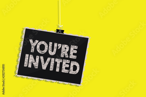 Writing note showing You re are Invited. Business photo showcasing Please join us in our celebration Welcome Be a guest Hanging blackboard message communication sign yellow background