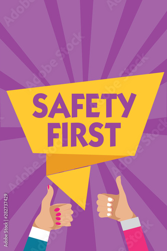 Text sign showing Safety First. Conceptual photo Avoid any unnecessary risk Live Safely Be Careful Pay attention Man woman hands thumbs up approval speech bubble origami rays background photo