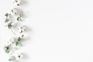 Flowers creative composition. Cotton flowers, eucalyptus branches and leaves on white background. Flat lay, top view, copy space