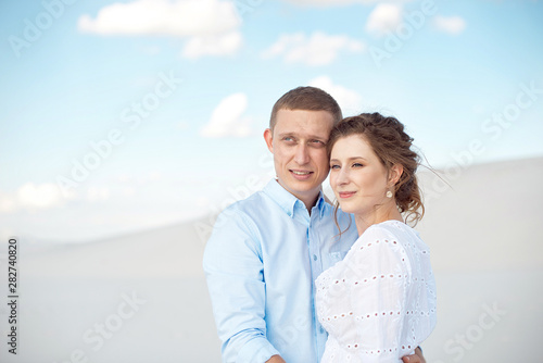 Young man and woman hugging on a background of white sand, dunes. Love story in the void © Viktoria