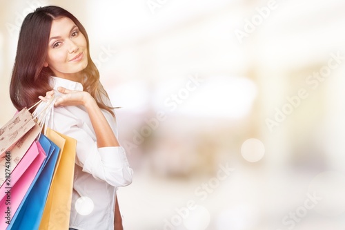 Young woman with shopping bags on blurred shopping background