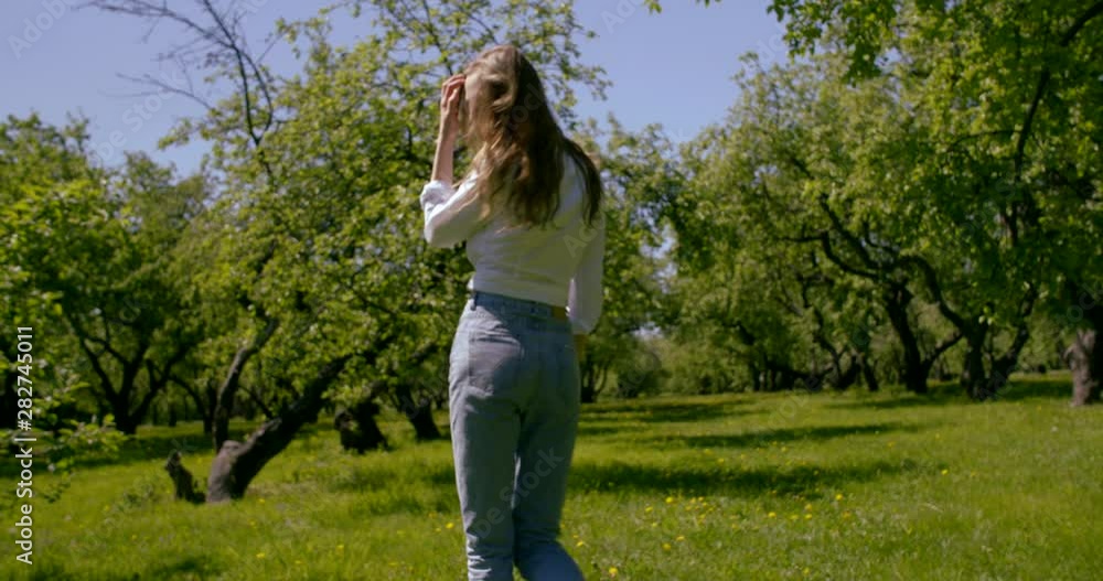 happy female model is strolling between trees in botanical garden in sunny spring day happy female model is strolling between trees in botanical garden in sunny spring day