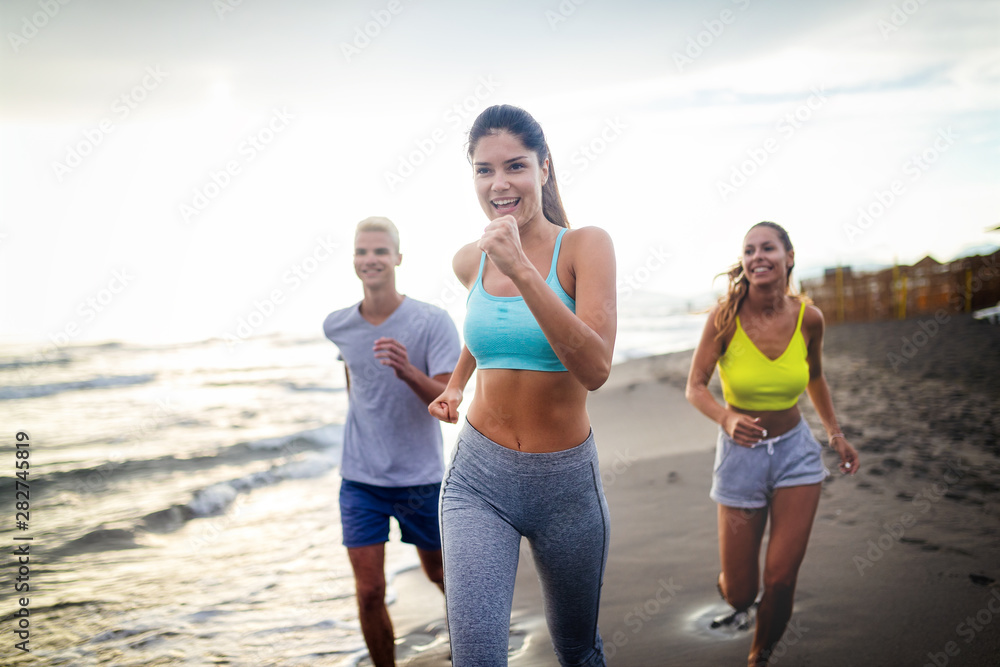 Group of athletes running on ocean front. Friends in sportswear training together outdoors. Group of athletes running on ocean front. Friends in sportswear training together outdoors.